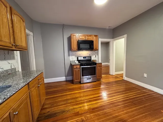 a kitchen with stainless steel appliances wooden floor and a refrigerator