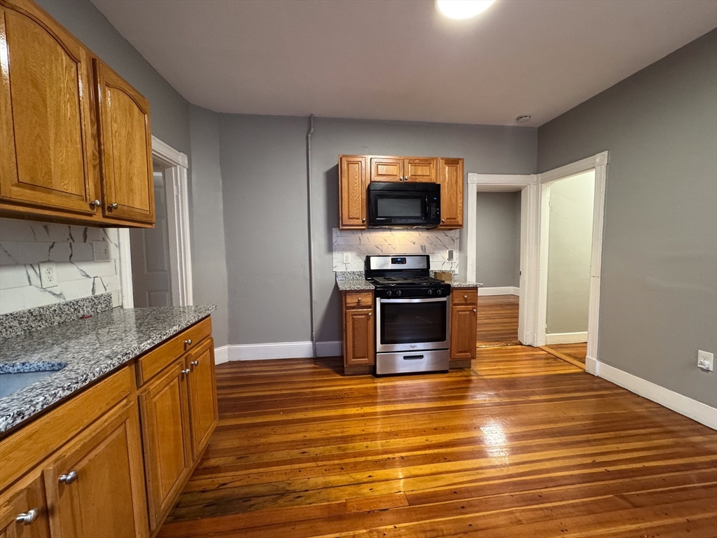 12 Dalrymple Street, Unit 2 Boston, MA 02130 - Photo 5 of 21 a kitchen with stainless steel appliances granite countertop a sink a stove and microwave
