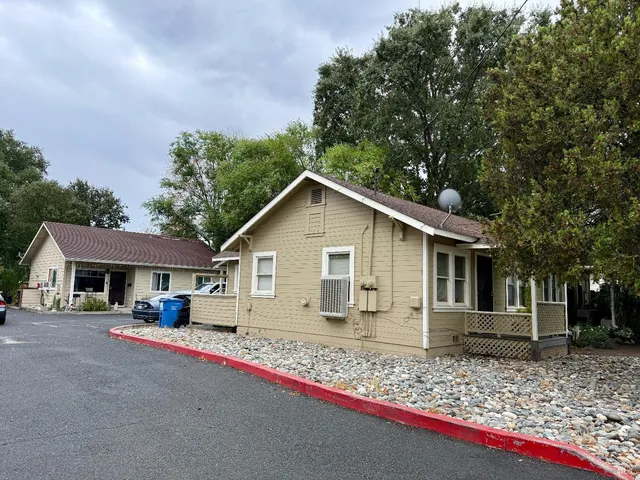 a view of a house with a yard and large trees
