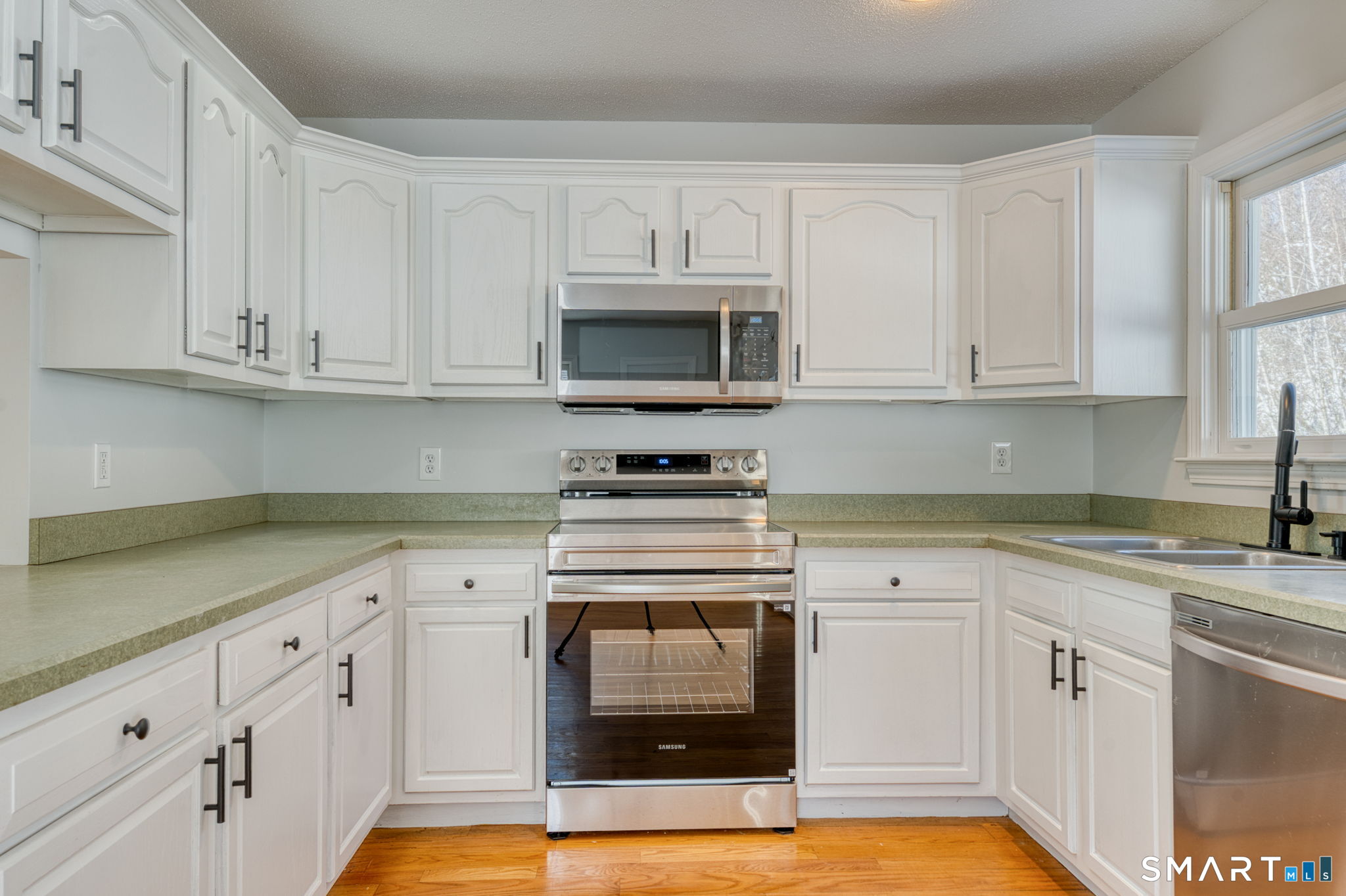 350 Bristol Street, Unit C1 Waterbury, CT 06708 - Photo 25 of 40 a kitchen with granite countertop white cabinets and white appliances