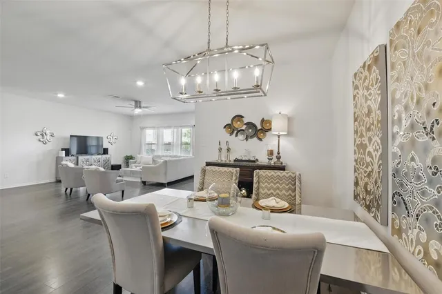 a very nice looking dining room with furniture a chandelier and wooden floor