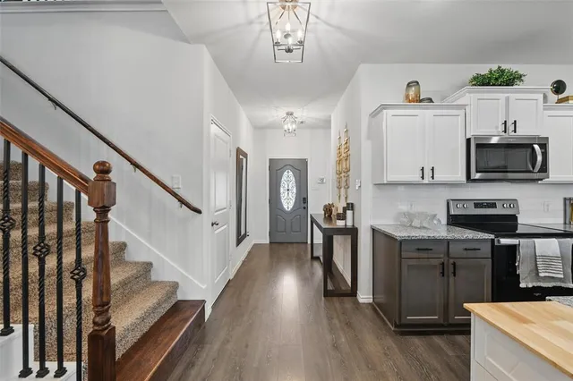 a kitchen with stainless steel appliances granite countertop a refrigerator a stove top oven a chimney wooden floor and cabinets