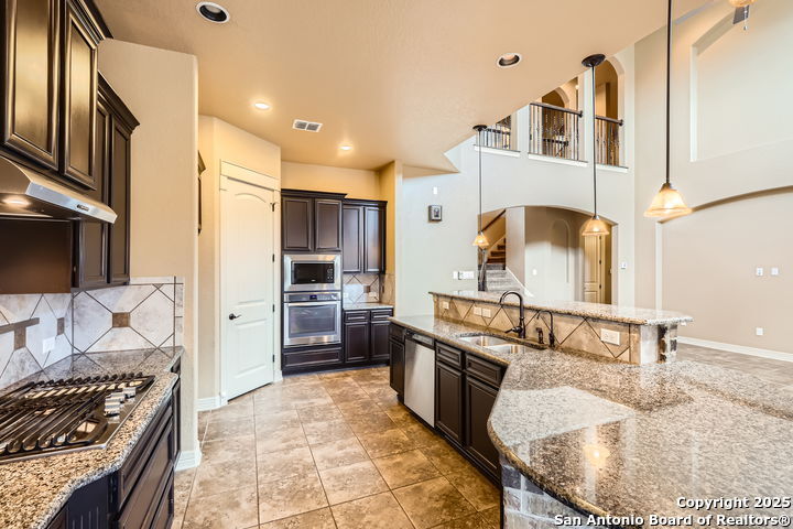 14722 Rifleman Road San Antonio, TX 78254 - Photo 8 of 37 a kitchen with kitchen island granite countertop a sink stove and refrigerator
