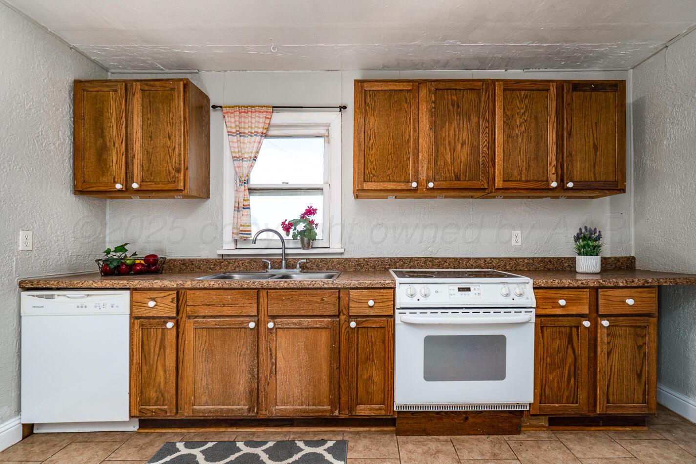 8015 Upton Road Amarillo, TX 79119 - Photo 5 of 16 a kitchen with granite countertop a stove a sink dishwasher and cabinets with wooden floor