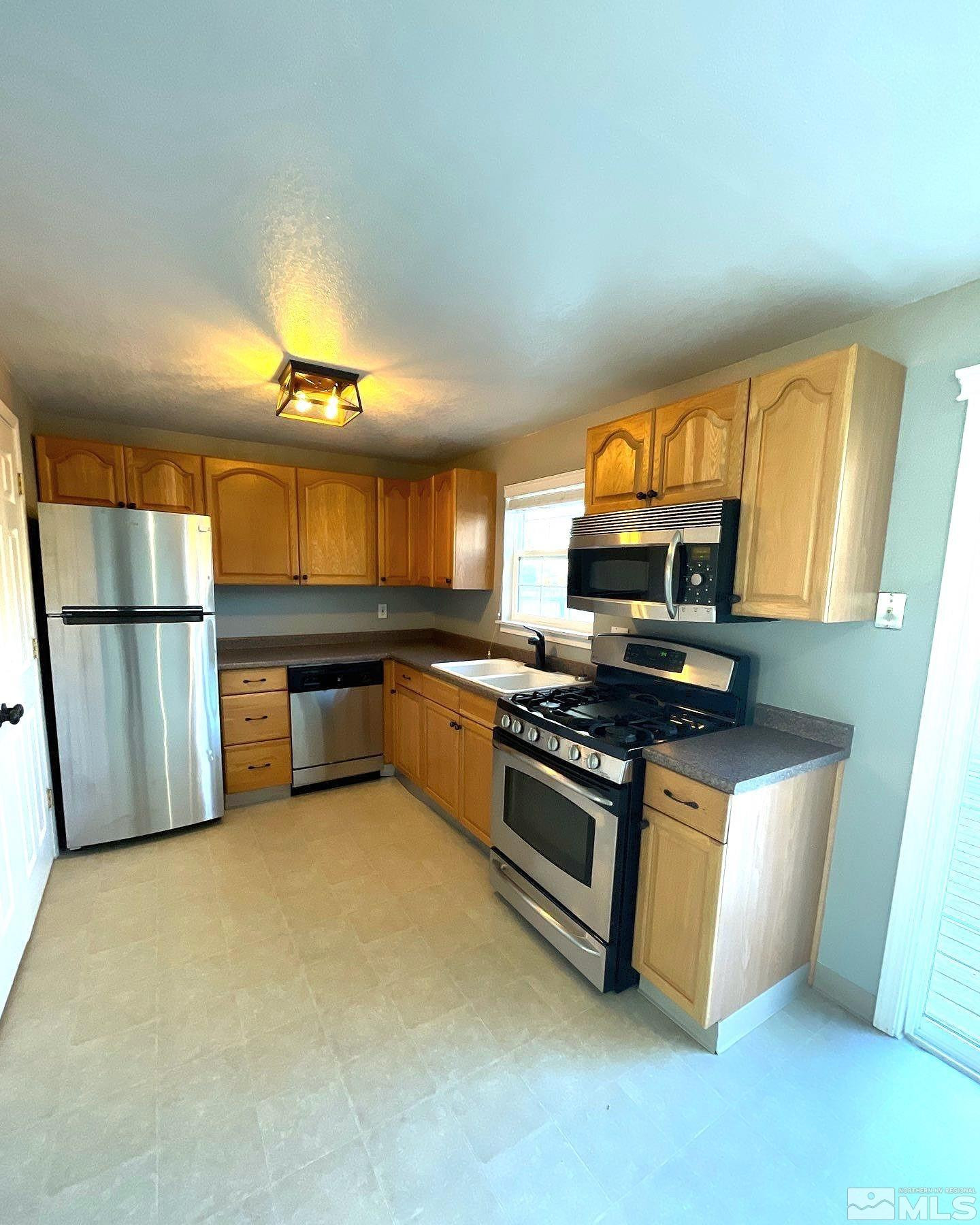 405 Kess Way Reno, NV 89506 - Photo 4 of 14 a kitchen with stainless steel appliances granite countertop a stove top oven a sink and a refrigerator