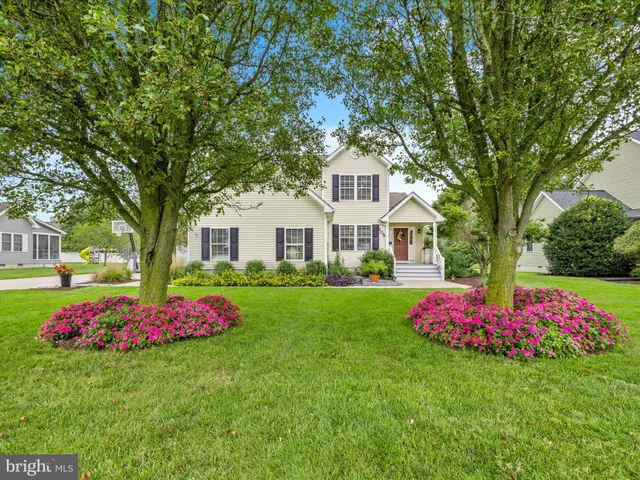a front view of a white house with a yard and trees