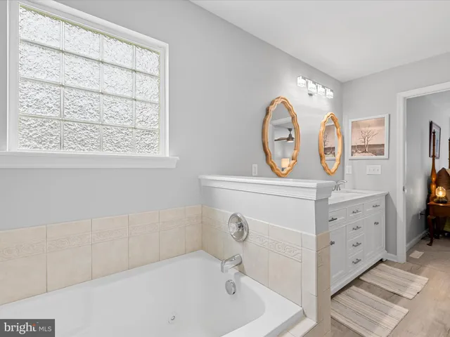 a bathroom with a tub sink and mirror