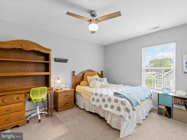 a bedroom with a bed a desk and chair with the bookshelf