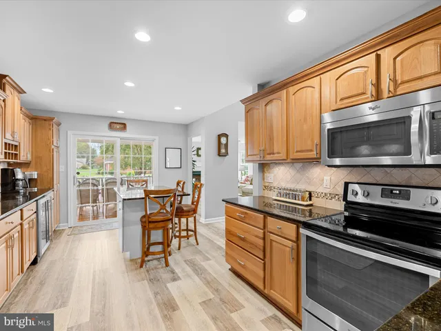 a kitchen with stainless steel appliances granite countertop a stove top oven a sink dishwasher a dining table and chairs with wooden floor