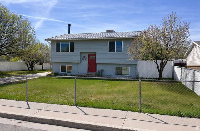 Raised ranch featuring a fenced front yard and a metal roof