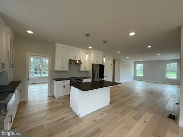 a large kitchen with stainless steel appliances a large counter top a stove and a wooden floors