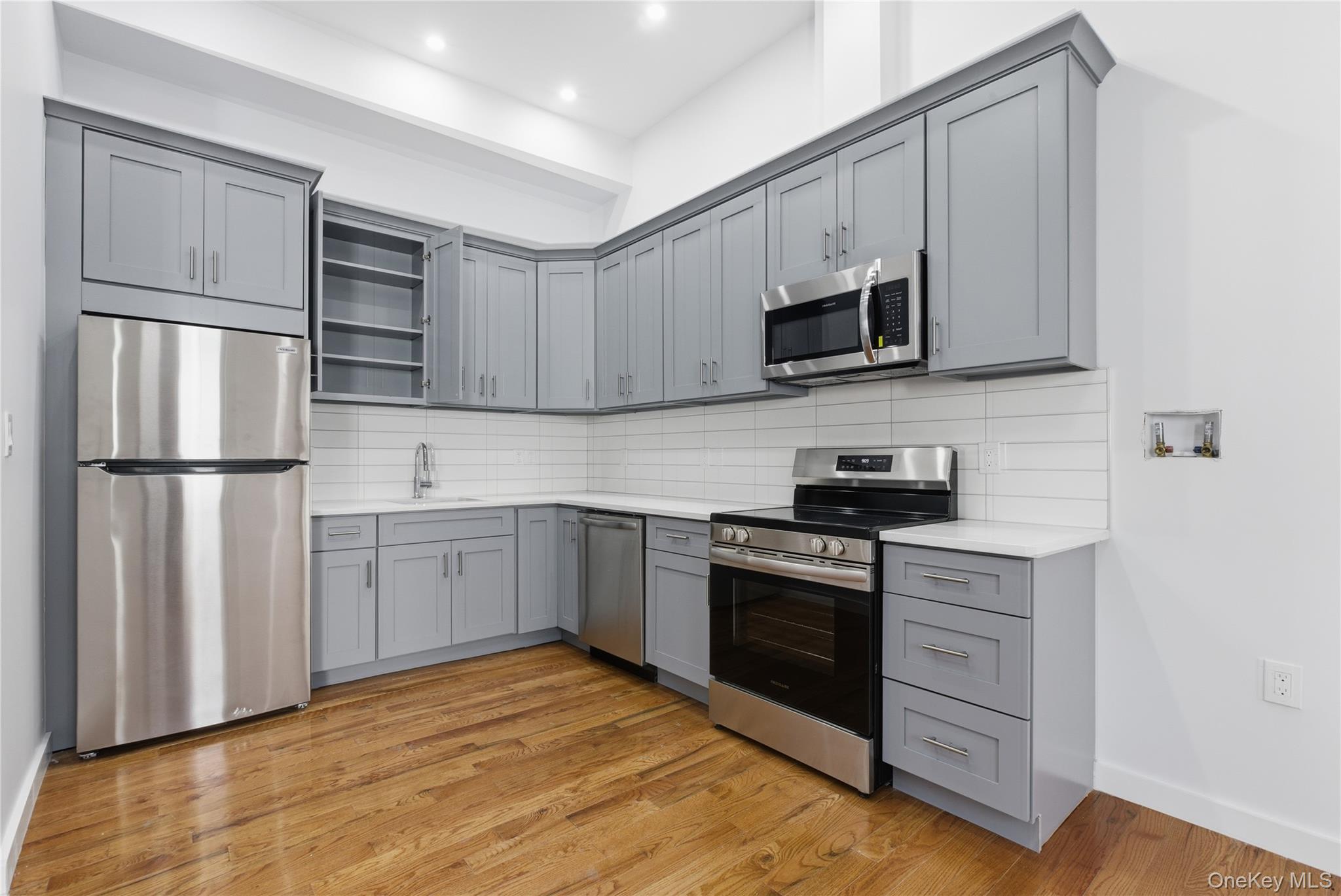 99 Main Street, Unit 2B Brewster, NY 10509 - Photo 1 of 11 a kitchen with stainless steel appliances granite countertop a refrigerator stove a sink and dishwasher with wooden floor