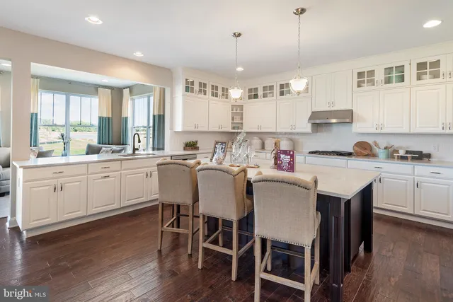 a kitchen with a dining table chairs cabinets wooden floor and appliances