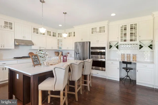 a kitchen with stainless steel appliances kitchen island granite countertop a table chairs and a refrigerator