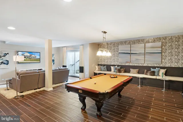 a room with stainless steel appliances kitchen island granite countertop a stove a refrigerator a dining table and chairs with wooden floor