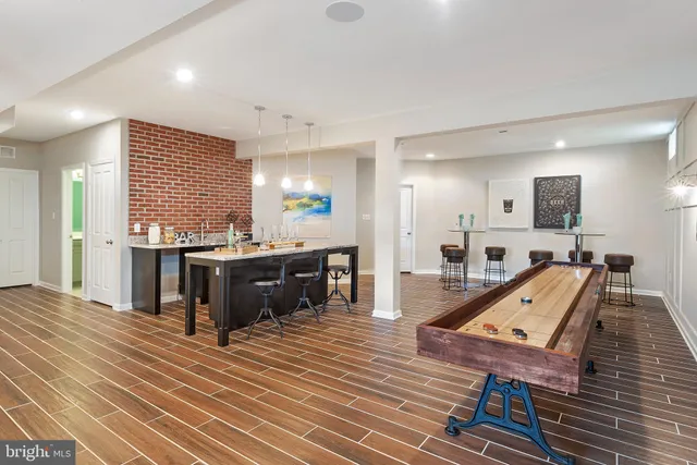 a living room with chairs kitchen view and a wooden floor
