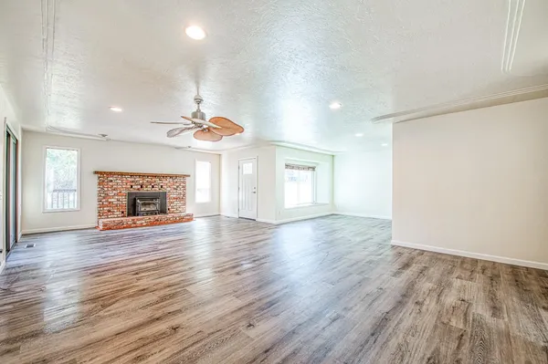 an empty room with wooden floor fireplace and windows