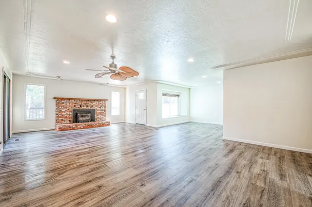 an empty room with wooden floor fireplace and windows