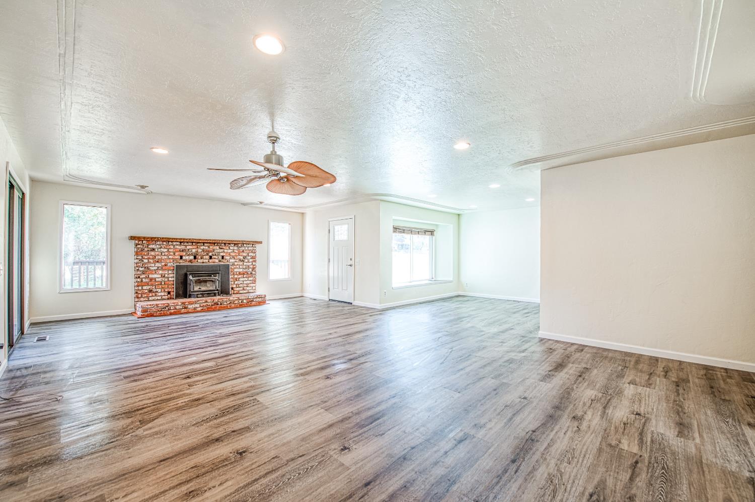 33988 Shaver Springs Road Auberry, CA 93602 - Photo 12 of 34 an empty room with wooden floor fireplace and windows