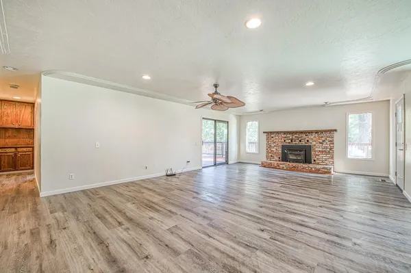 an empty room with wooden floor fireplace and windows