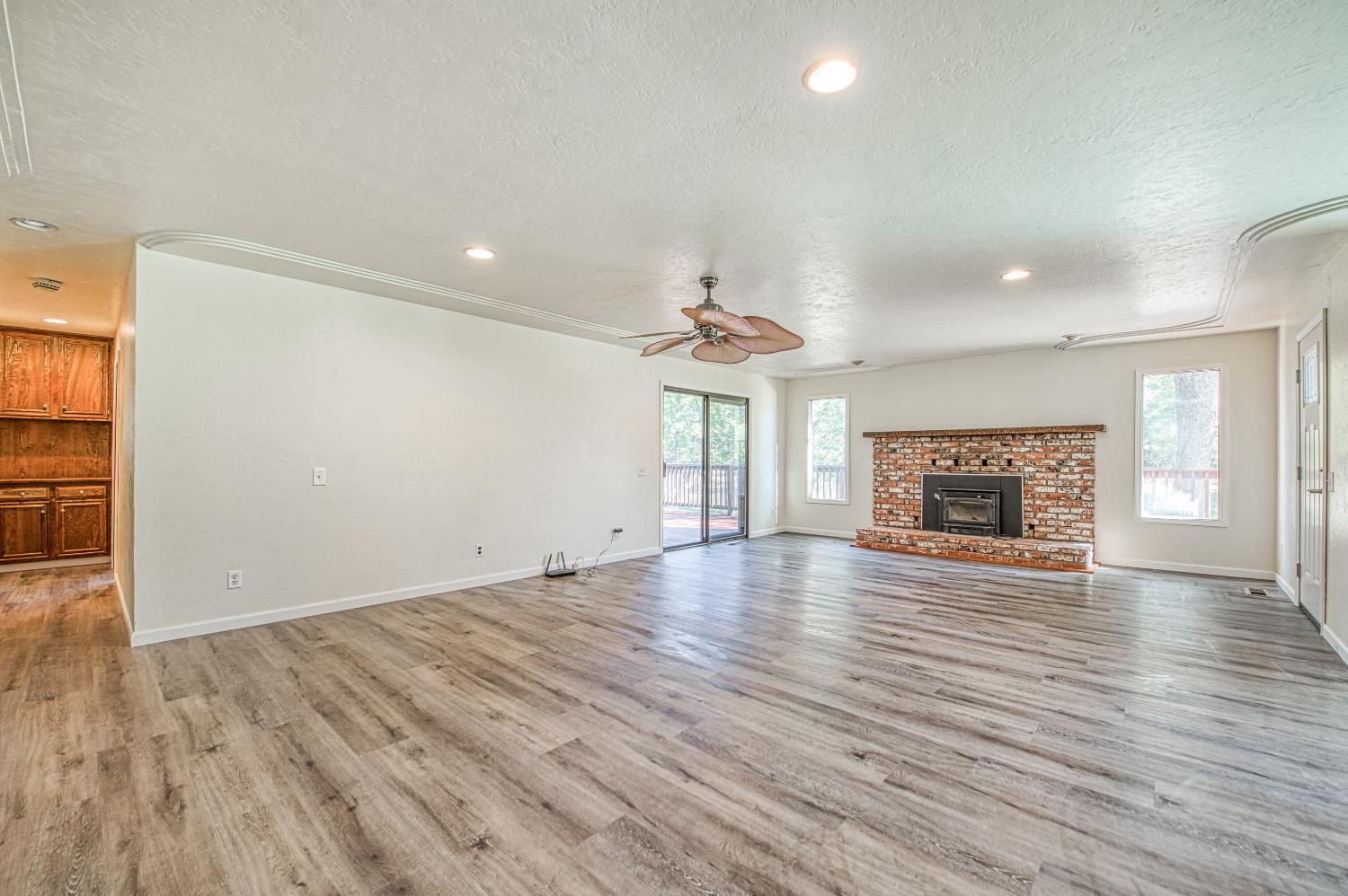 33988 Shaver Springs Road Auberry, CA 93602 - Photo 13 of 34 an empty room with wooden floor fireplace and windows