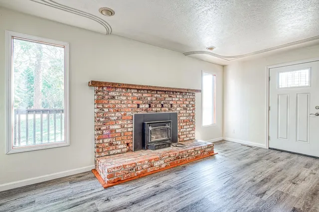an empty room with wooden floor fireplace and windows