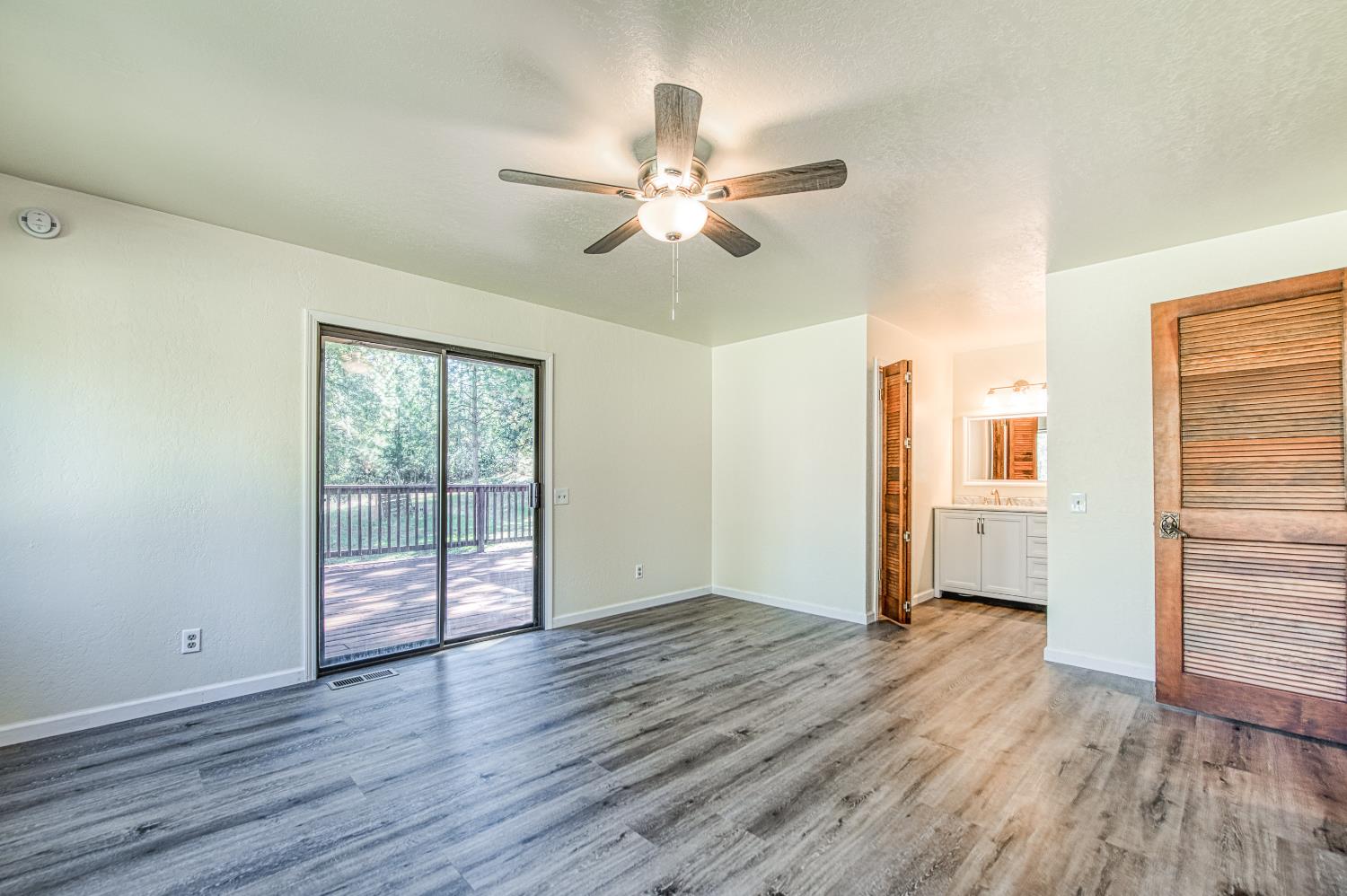 33988 Shaver Springs Road Auberry, CA 93602 - Photo 21 of 34 an empty room with wooden floor chandelier fan and windows