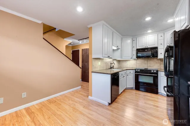 a kitchen with granite countertop a refrigerator stove top oven and sink