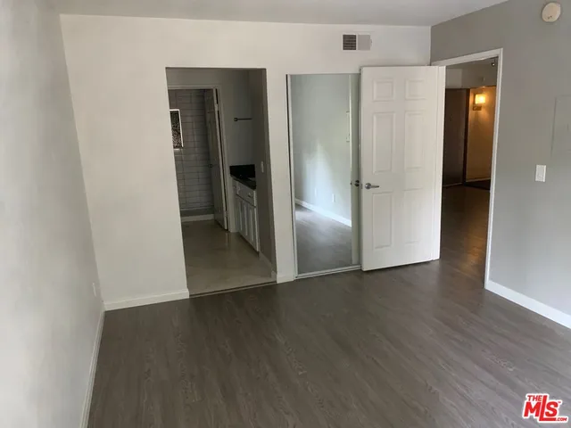 an empty room with wooden floor & closet area