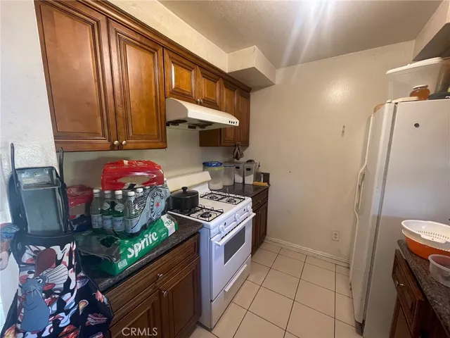 a kitchen with stainless steel appliances granite countertop a stove a refrigerator and a wooden cabinets