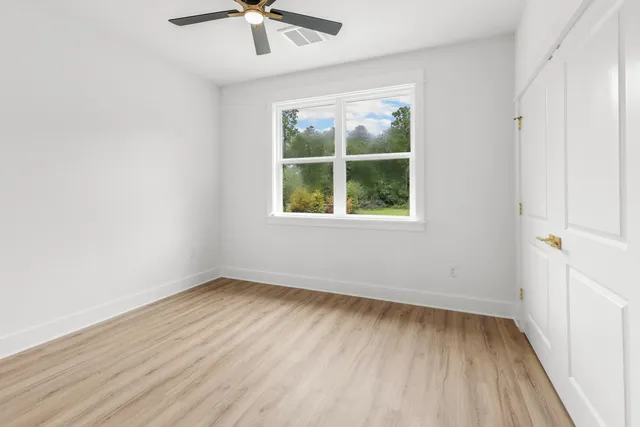 an empty room with a window and a ceiling fan