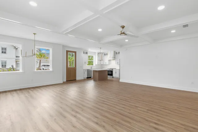 an empty room with wooden floor chandelier and windows