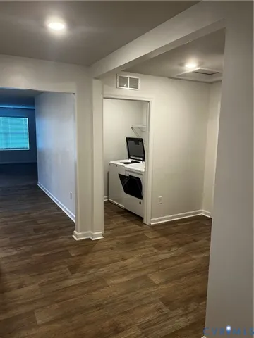 a view of a kitchen from an empty room and wooden floor