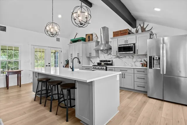 a kitchen with kitchen island stainless steel appliances a table chairs in it and wooden floors