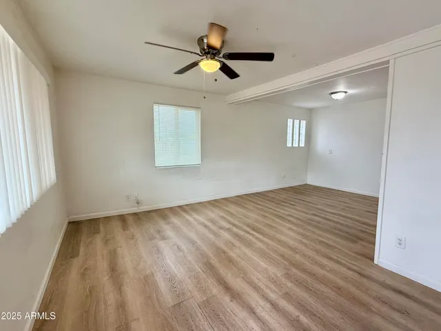 a view of empty room with wooden floor and fan