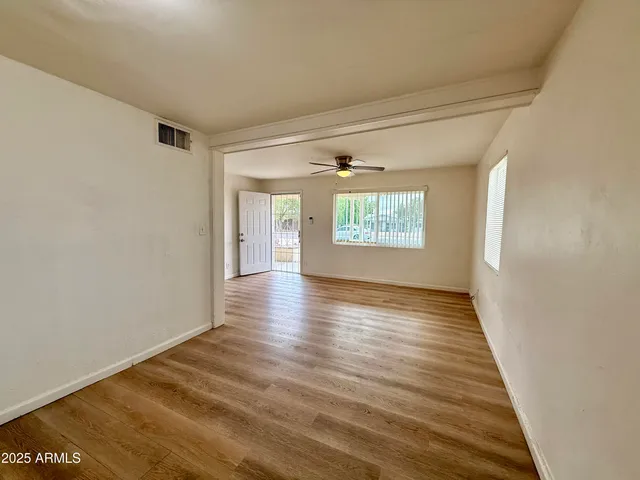 a view of an empty room with wooden floor and a window
