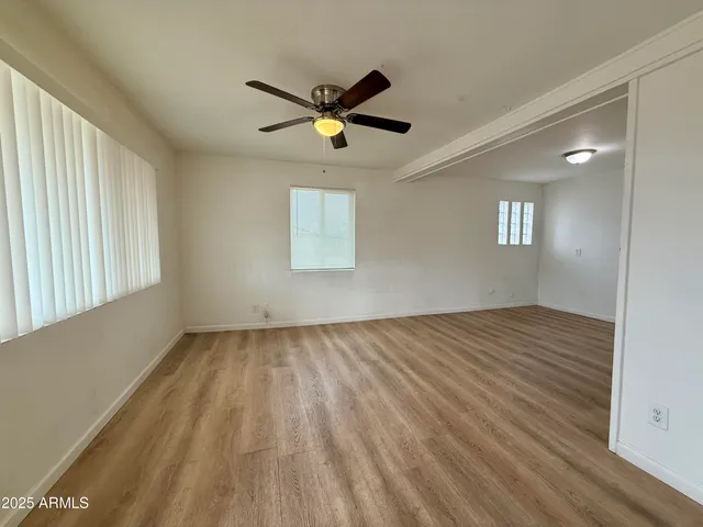 a view of empty room with wooden floor and fan