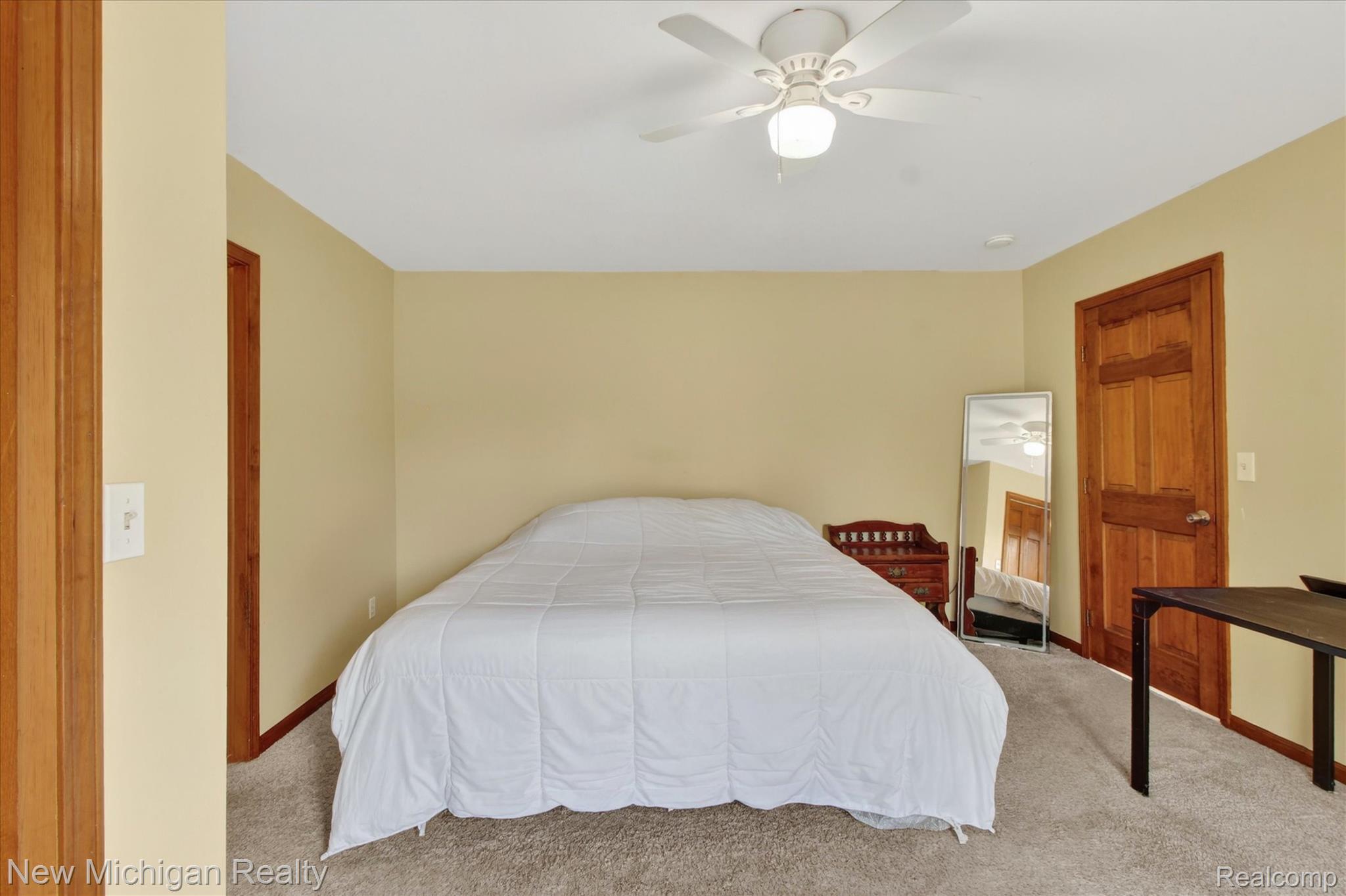 22623 11 Mile Road Reed City, MI 49677 - Photo 20 of 47 Carpeted room with a ceiling fan light fixture, light yellow painted walls, and wood-finish doors and trim