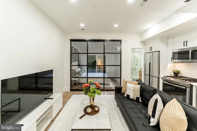 a living room with furniture a flat screen tv and a refrigerator