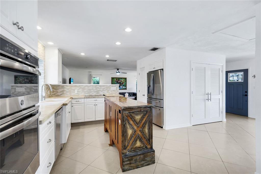 4352 Parrot Avenue Naples, FL 34104 - Photo 11 of 27 a kitchen with white cabinets and stainless steel appliances