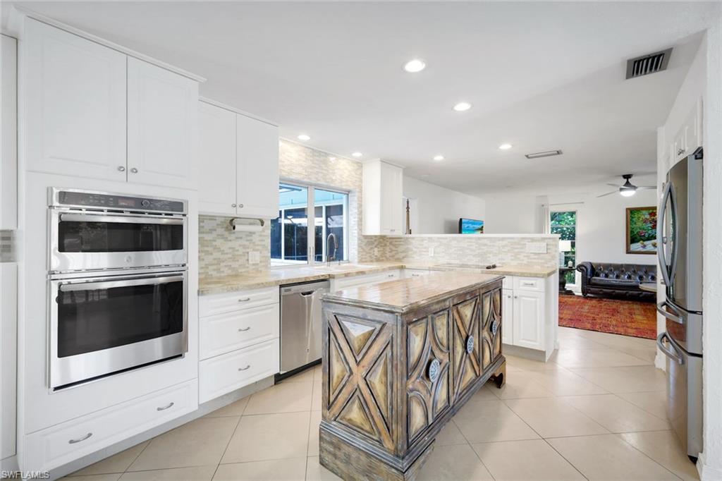 4352 Parrot Avenue Naples, FL 34104 - Photo 10 of 27 a kitchen with stainless steel appliances kitchen island granite countertop a sink and cabinets