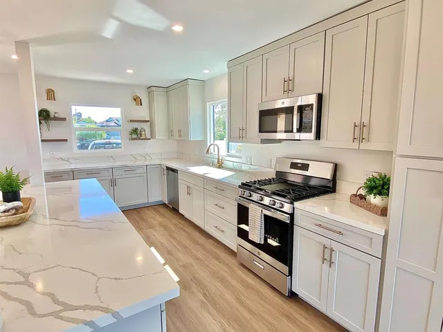 a kitchen with stainless steel appliances white cabinets and wooden floors