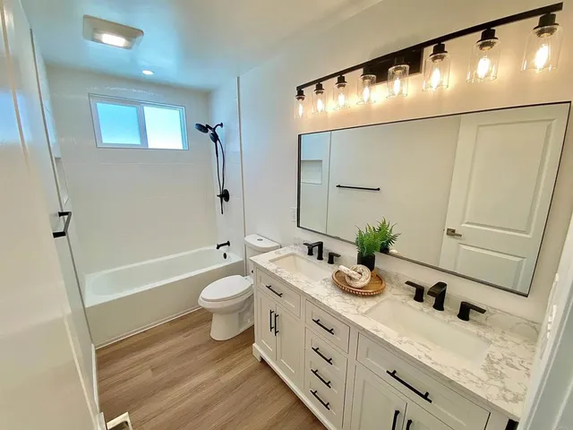 a bathroom with a granite countertop sink a toilet a mirror and shower