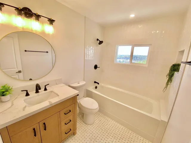 a bathroom with a double vanity sink toilet mirror and bathtub