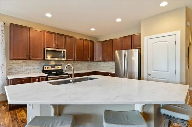 a kitchen with stainless steel appliances granite countertop a refrigerator a stove a sink a counter space and cabinets