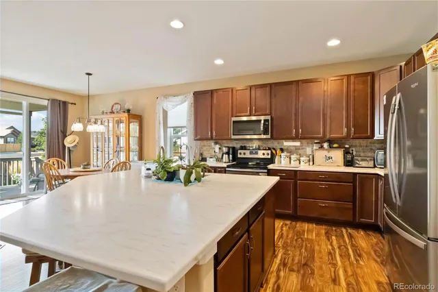 a kitchen with kitchen island granite countertop a stove top oven a sink dishwasher a dining table and chairs with wooden floor