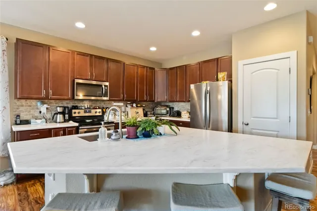 a kitchen with stainless steel appliances granite countertop a refrigerator a stove a sink a counter space and cabinets