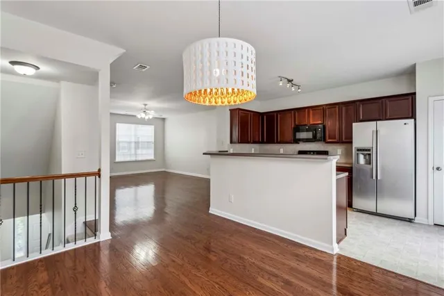 a kitchen with stainless steel appliances granite countertop a refrigerator a stove a sink dishwasher and a dining table with wooden floor