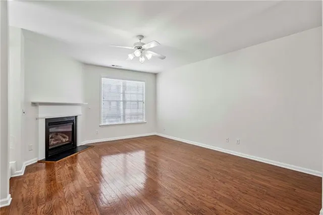 a view of empty room with wooden floor fireplace and fan