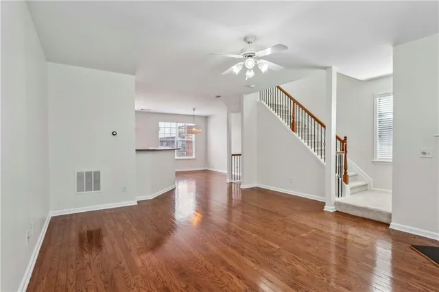 a view of an empty room with wooden floor and staircase